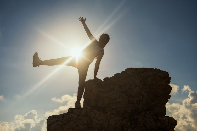 silhouette-happy-hiking-woman-raise-hand-leg-after-reaching-top-hill-with-sunset_33842-1236